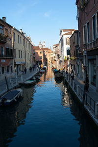 Canal amidst buildings in city against sky