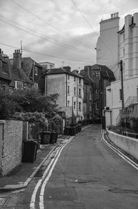 Road by buildings in city against sky