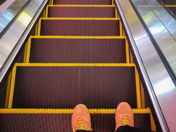 Low section of person standing on escalator