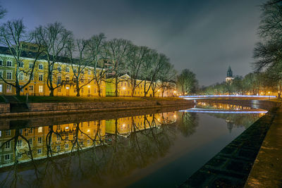 Illuminated bridge over river against sky at night