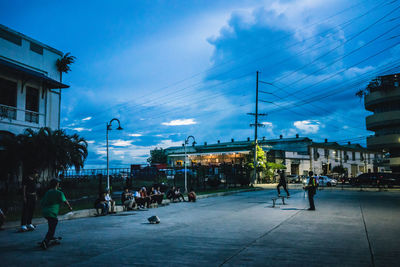 People walking on road in city against sky