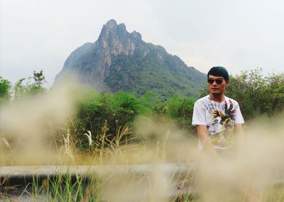 Man wearing sunglasses while sitting against mountain