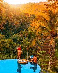Couple having breakfast on the edge of the pool in the middle of the jungle in bali