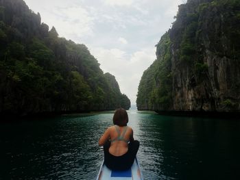 Rear view of woman sitting in boat on sea against sky