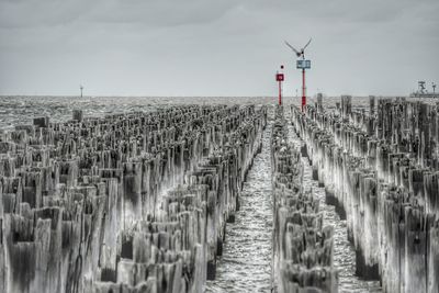 Wooden posts on beach against sky