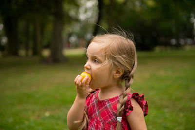 Cute girl eating food while looking away at park