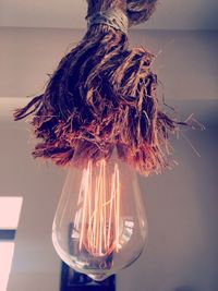 Low angle view of illuminated light bulb hanging at home