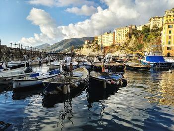 Boats moored at harbor by buildings in city