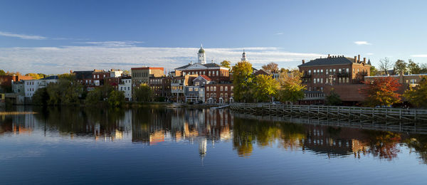 Buildings by river against sky