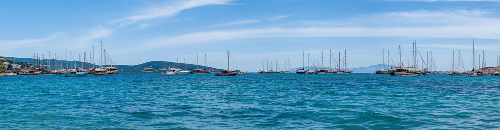 Yachts and sail boats anchored in calm waters of bodrum shallow moon-shaped bay in turkey.