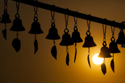 Close-up of silhouette lanterns hanging on tree at sunset