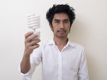 Portrait of young man standing against white background