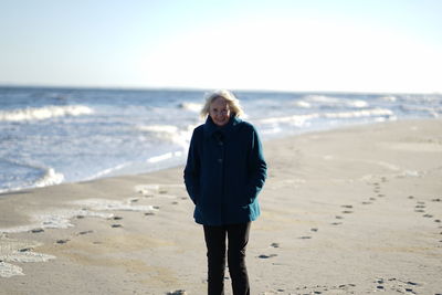 Full length portrait of woman standing on beach against sky