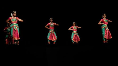 Group of people dancing against black background