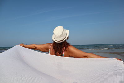 Rear view of woman holding scarf at beach