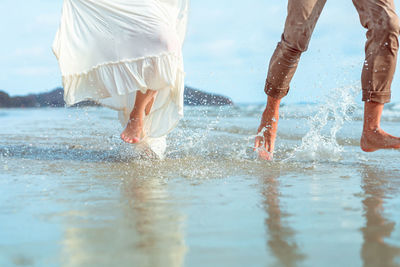 Low section of couple running in sea