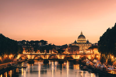 Illuminated bridge over river against sky at sunset