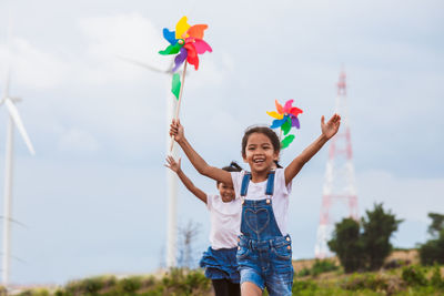 Sisters playing with pinwheel toys on land with windmills in background