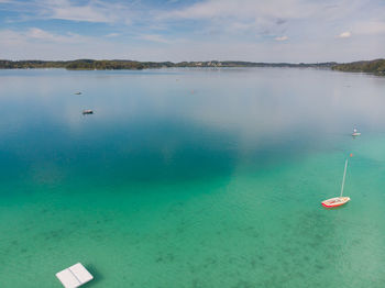 Scenic view of lake wörthsee with turwquise water against sky