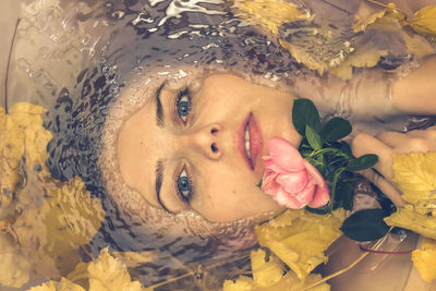 Close-up portrait of young woman with autumn leaves in bathtub
