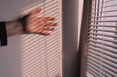 Close-up of hand on wall by window