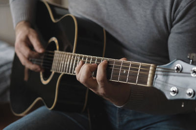 Midsection of man playing guitar