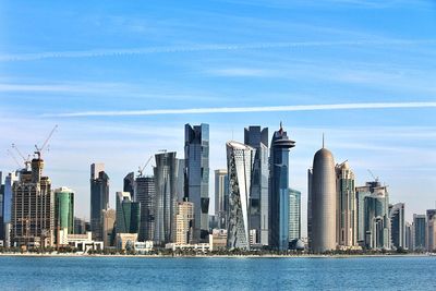 Sea against doha tower and modern buildings in city