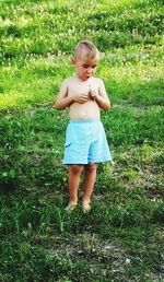 Full length of shirtless boy standing on field