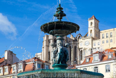 Low angle view of fountain against buildings in city