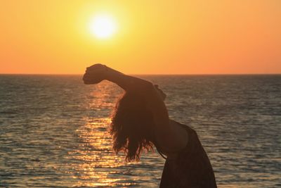 Silhouette person in sea against sky during sunset