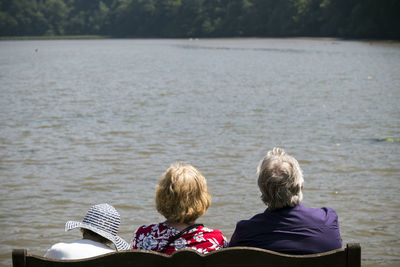 Rear view of people sitting at lake