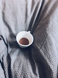 High angle view of coffee cup on bed