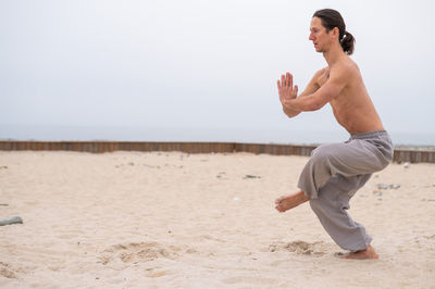 Full length of woman exercising at beach