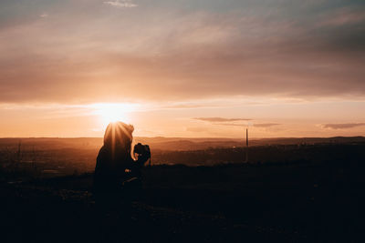 Man photographing on field against sky during sunset