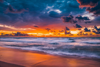 Scenic view of sea against dramatic sky during sunset