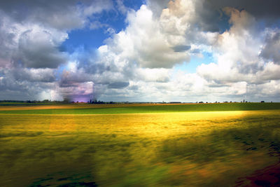 Scenic view of field against cloudy sky