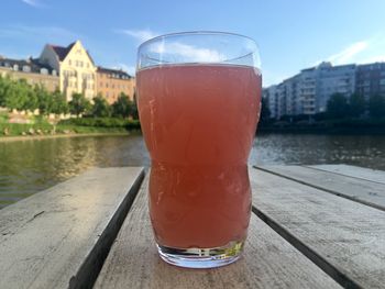 Close-up of juice in drinking glass on table by lake
