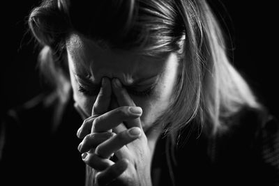 Close-up of depressed woman against black background