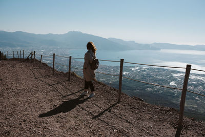 Rear view of woman looking at sea against mountains