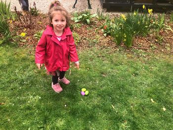 Portrait of girl pointing at easter eggs on grassy field