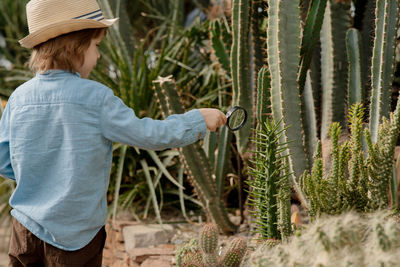 Preschooler boy inspecting desert cactus using magnifying glass. in the desert