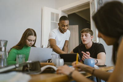 Multiracial friends studying together at dining table