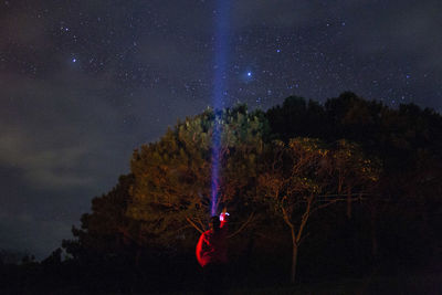 Man against illuminated trees against sky at night