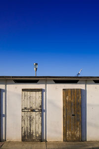 Cropped built structure with closed doors against blue sky