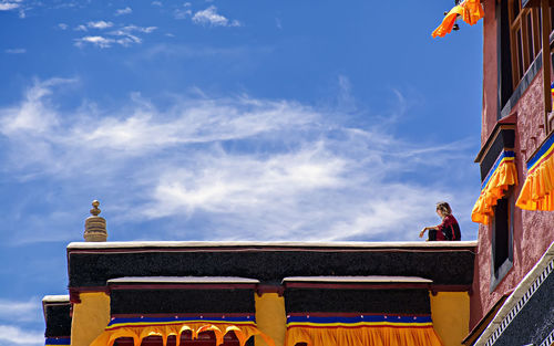 Low angle view of woman sitting on temple against sky