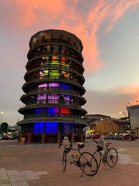 Bicycles against illuminated city at sunset