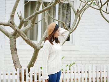 Woman standing by fence against plants