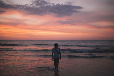 Man walking at beach during sunset