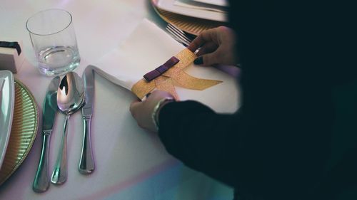 Midsection of woman arranging napkin on table