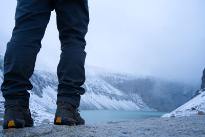 Low section of man standing on snowcapped mountain